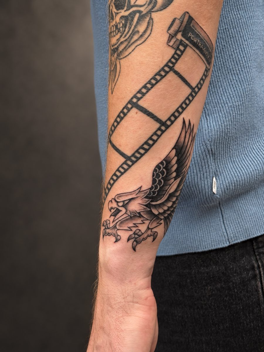 Blackwork tattoo met een filmstrip en gevleugeld wezen op de onderarm, gezet in Lelystad