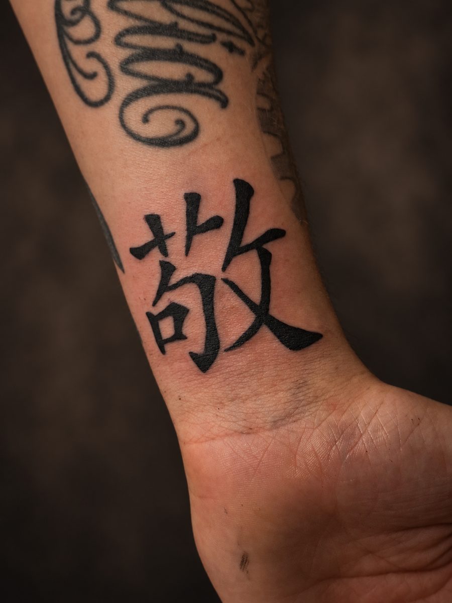 Blackwork tattoo van een japans karakter in massief zwart op de pols, gezet bij EmmsTattoo in Lelystad
