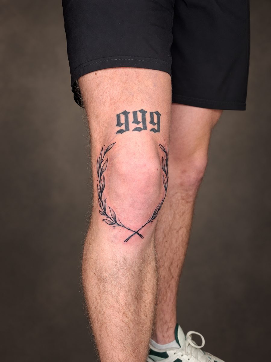 Fineline tattoo van cijfers met een hartlijn rond de knie, gezet bij EmmsTattoo in Lelystad
