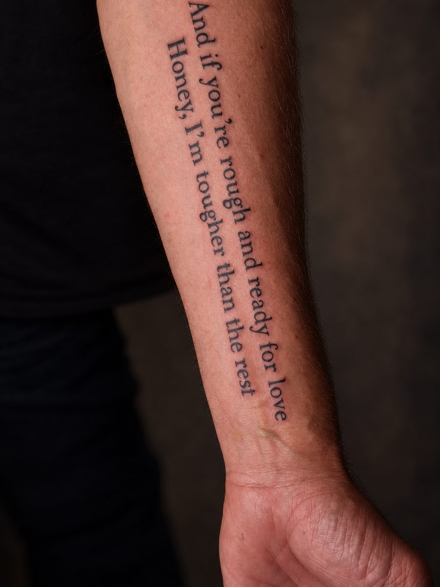 Fineline tattoo van een citaat in kleine letters langs de onderarm, gezet bij EmmsTattoo in Lelystad