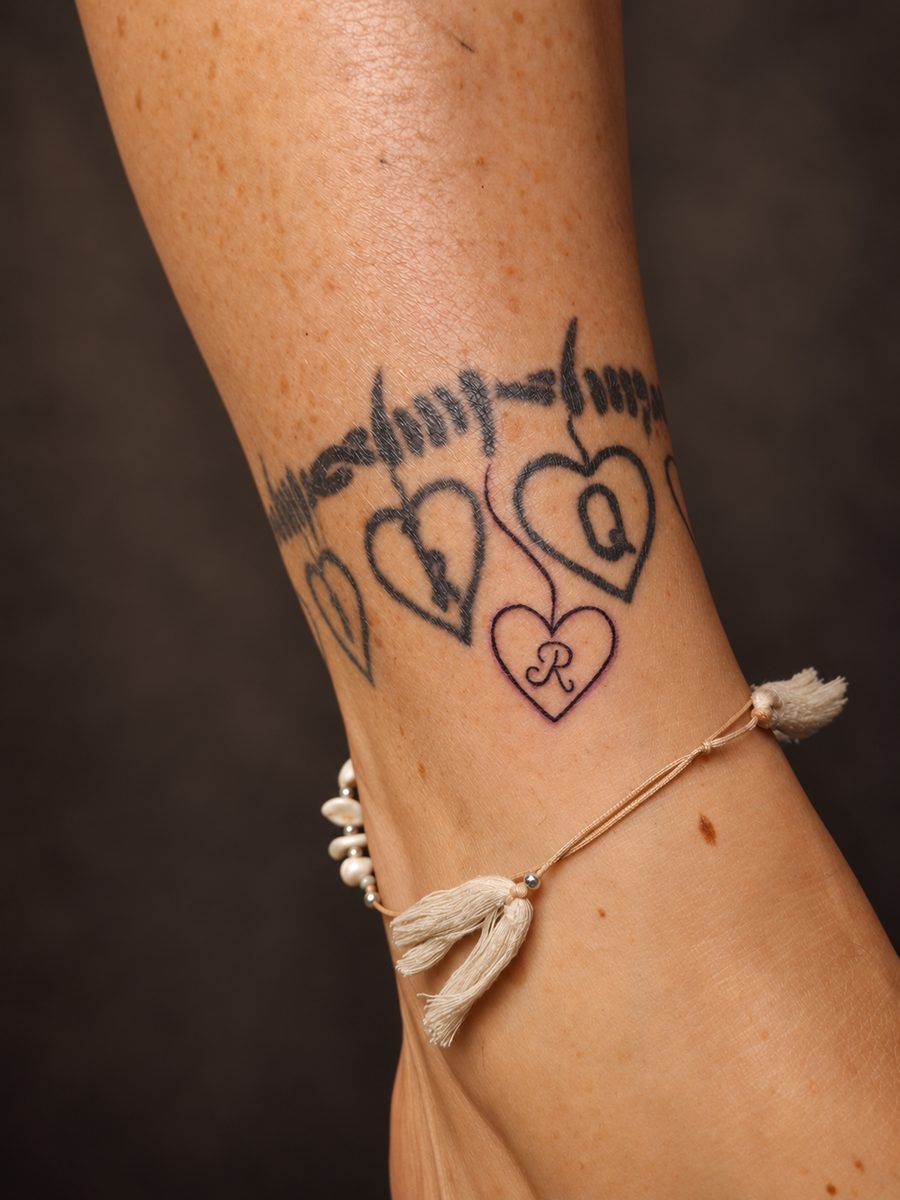 Fineline tattoo van een enkelbandje met hartjes en een strikje, gezet bij EmmsTattoo in Lelystad