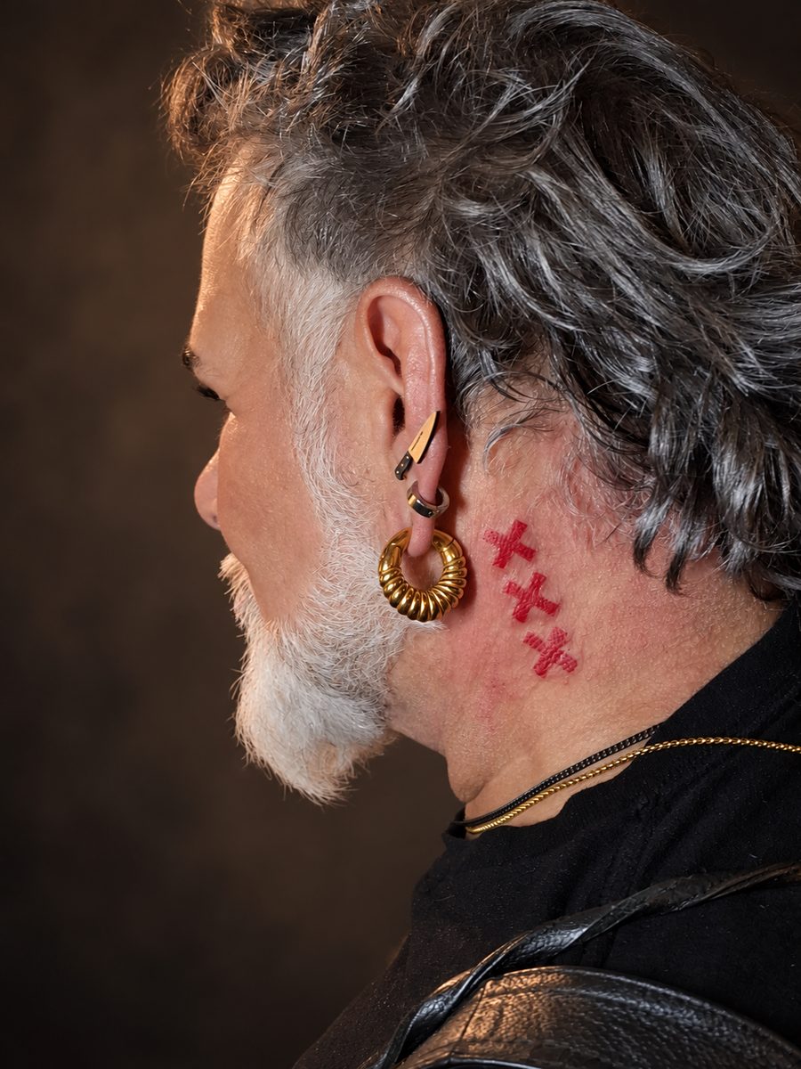 Fineline tattoo van drie kleine kruisjes op de wang, gezet bij EmmsTattoo in Lelystad