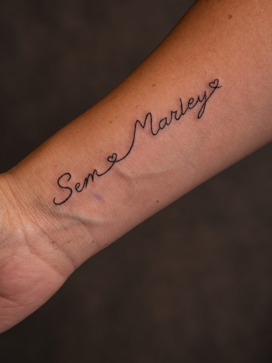 Fineline tattoo van een naam in handschrift langs de onderarm, gezet bij EmmsTattoo in Lelystad