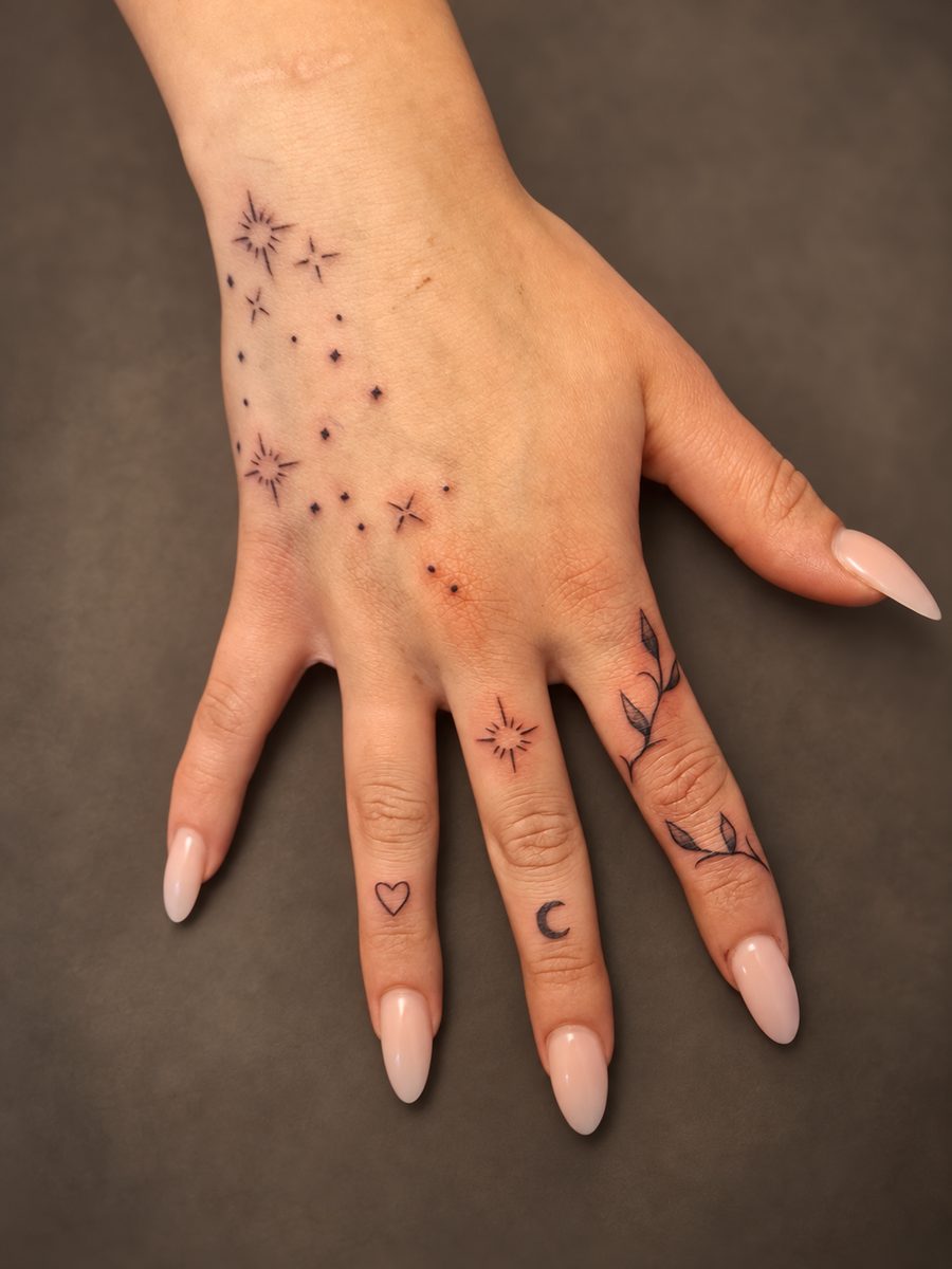 Fineline tattoo van sterretjes en kleine symbolen op hand en vingers, gezet bij EmmsTattoo in Lelystad