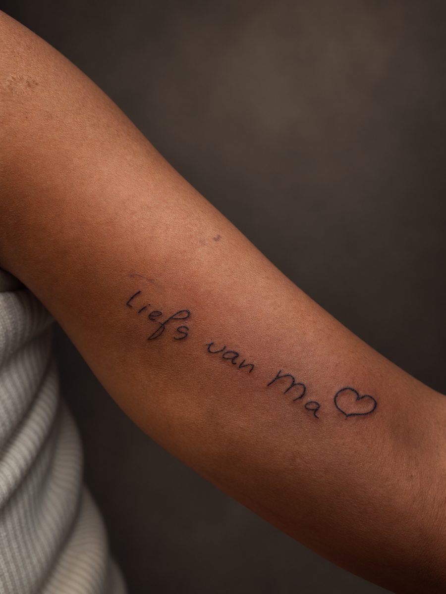 Fineline tattoo van een handgeschreven tekstregel met hartje op de onderarm, gezet bij EmmsTattoo in Lelystad