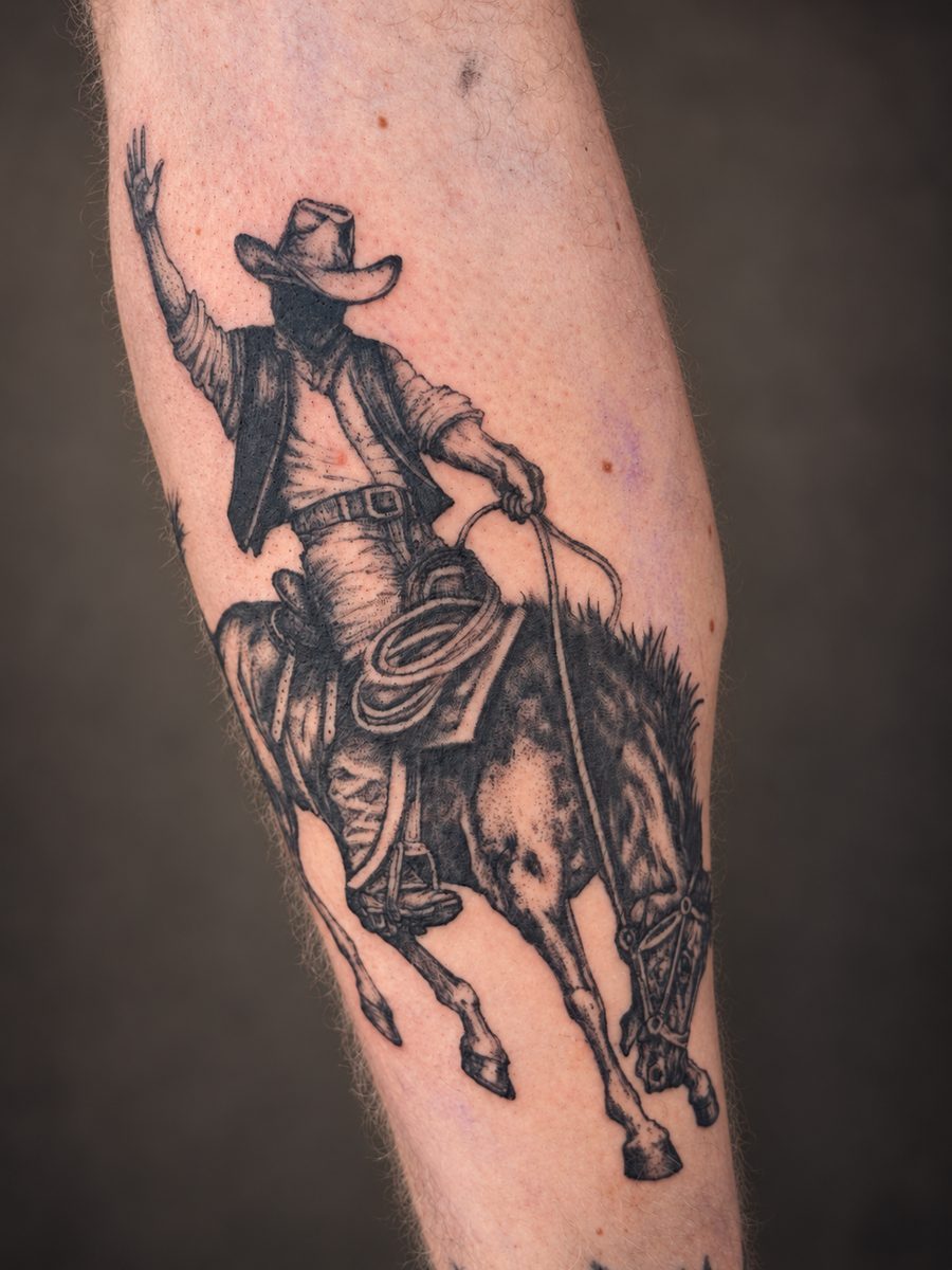 Illustrative tattoo van een cowboy op een steigerend paard op de onderarm