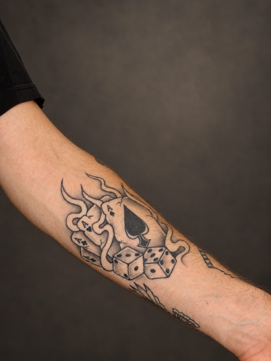 Illustrative tattoo van een schoppenaas met dobbelstenen op de onderarm, gezet in Lelystad